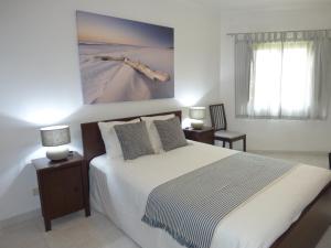 a bedroom with a bed and a painting on the wall at Milfontes Paradise in Vila Nova de Milfontes