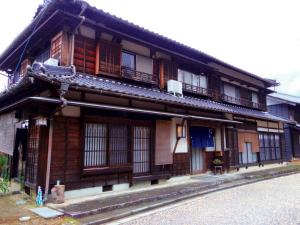 an old wooden building with windows on a street at Guest House Motomiya in Nakatsugawa