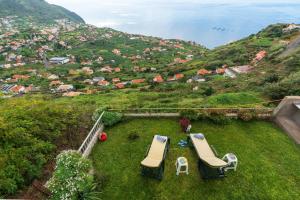 two lounge chairs and a table on a field of grass at Casa da Tenda in Arco da Calheta