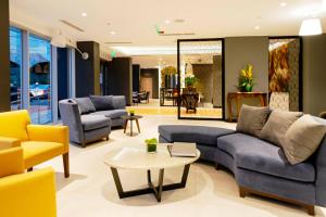 una sala de estar con sofás azules y sillas amarillas. en Mercure Ariosto Lima, en Lima