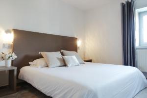 a bedroom with a large bed with white sheets and pillows at Hotel La Chaumette in Privas