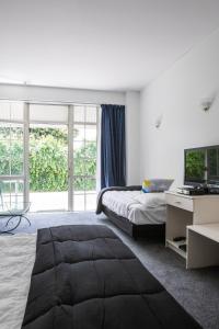 a bedroom with a bed and a desk with a television at U Studios Paraparaumu Beach in Paraparaumu Beach