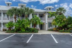 a white building with palm trees in a parking lot at GreenLinks Golf View Villa Mustang at Lely Resort in Naples