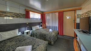 a hotel room with two beds and a television at Queenstown Motor Lodge in Queenstown