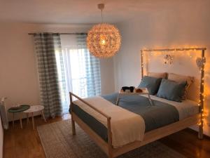 - une chambre avec un grand lit et un lustre dans l'établissement Ericeira Luxury Apartment on a private condo, à Ericeira