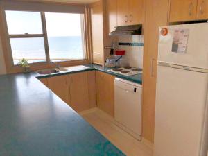 a kitchen with a white refrigerator and a window at Toowoon Bay Beachfront Apartment in The Entrance