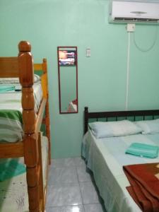 a bedroom with two beds and a mirror at Pousada Cabral in São Gabriel