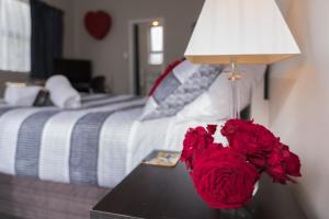 um vaso de rosas vermelhas sentado numa mesa ao lado de uma cama em Quiet Boutique Generous Breakfast em Palmerston North