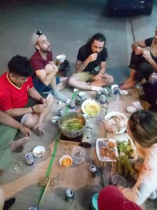 un gruppo di persone seduti sul pavimento che mangiano cibo di Hung Kiet Guesthouse a Hà Tiên