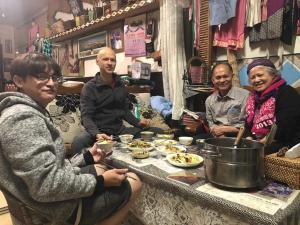 eine Gruppe von Menschen, die an einem Tisch mit Essen sitzen in der Unterkunft Dai Yi Shia B&B in Fushi