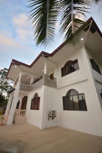 a white house with a palm tree in front of it at White Summerville Tourist Inn in Busuanga