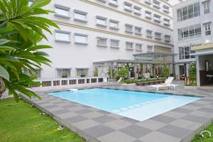a swimming pool in front of a building at La Lisa Hotel Surabaya in Surabaya