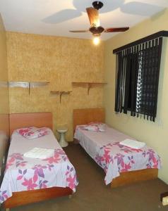 a bedroom with two beds and a ceiling fan at Hotel Capriccio Mauá in Mauá