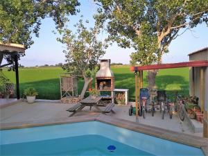 ein Hinterhof mit einer Feuerstelle neben einem Swimmingpool in der Unterkunft Mas de Felip - Casa rural con piscina privada en el Delta - Deltavacaciones in Riumar