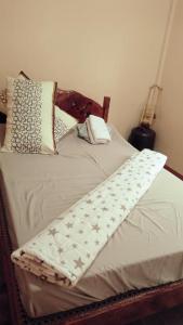 1 cama con edredón blanco y almohadas en AN Velayo Homestay (ANVEL), en Basco