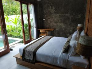 ein Schlafzimmer mit einem Bett und einem großen Fenster in der Unterkunft La Isla Villas Bali in Canggu