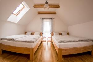 two beds in a attic room with a window at Chata Tatry Resort in Veľká Lomnica
