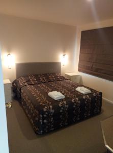 a bedroom with a bed with two towels on it at Patons Rock Beach Villas in Takaka