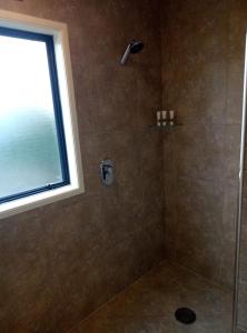 a shower with a glass door and a window at Patons Rock Beach Villas in Takaka