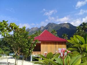 un edificio con tetto rosso e montagne sullo sfondo di Nusa Nalan Beach Resort a Rumah Olat