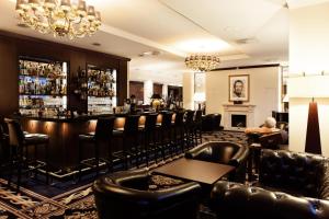 eine Bar in einem Hotel mit Ledersesseln in der Unterkunft Hotel Vier Jahreszeiten Starnberg in Starnberg