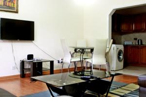 sala de estar con mesa, sillas y TV en Avon Apartments, en Lilongwe