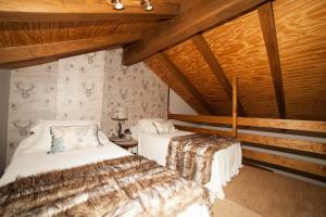 two beds in a room with wooden ceilings at Núcleo de Turismo Rural Valle de Iruelas in Las Cruceras
