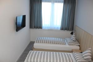 Habitación pequeña con 2 camas y TV. en Hotel Lumi en Friburgo de Brisgovia