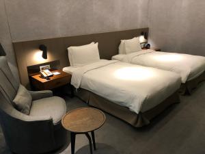 a hotel room with two beds and a chair at CHECK inn Taipei Nanjing in Taipei
