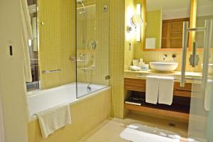a bathroom with a tub and a sink and a shower at Yas Island Rotana Abu Dhabi in Abu Dhabi