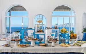 a table with plates of food on it with windows at Tramonto d'Oro in Praiano