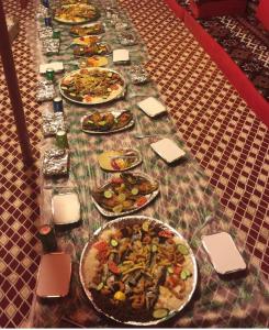 una mesa larga con muchos platos de comida. en Royal Tours Permanent Camp, en Umm Lajj