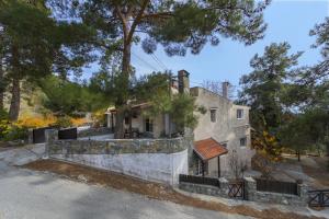 an old house with a stone wall and trees at Platres Forest View Cottage in Platres