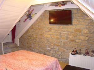 a bedroom with a stone wall with a flat screen tv at Kernel Bihan in Pont-lʼAbbé