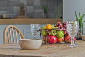 a basket of fruit on a table with two wine glasses at Kalimera Karpathos Exclusive Villas in Afiartis