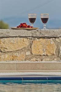 two glasses of wine on a wall next to a pool at Kalimera Karpathos Exclusive Villas in Afiartis