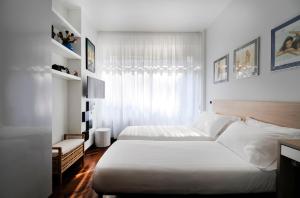 una camera bianca con due letti e una finestra di In+out Sempione Park Apartment a Milano