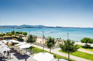 ein Strand mit Tischen und Sonnenschirmen und dem Wasser in der Unterkunft Hotel Alda Carril in Vilagarcia de Arousa