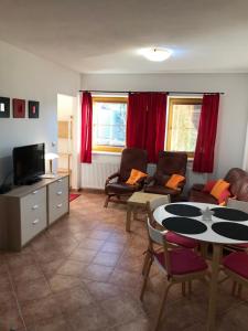 ein Wohnzimmer mit einem TV, einem Tisch und Stühlen in der Unterkunft Apartmány Lipno - Frymburk in Frymburk