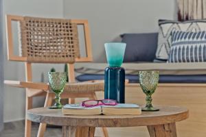 a table with a blue vase and glasses on it at Kalimera Karpathos Exclusive Villas in Afiartis