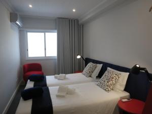 - une chambre avec un grand lit et une chaise rouge dans l'établissement RockInn Porto, à Vila Nova de Gaia