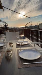 a table with plates and wine glasses on a deck at Seaview Deluxe Apartments Thessaloniki in Thessaloniki