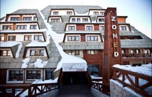 un gran edificio con nieve en el techo en Apartment 111 at Zoned Apart Hotel & Spa - Apartman 111 u hotelu Zoned, en Kopaonik