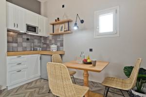 a kitchen with white cabinets and a wooden table and chairs at Kalimera Karpathos Exclusive Villas in Afiartis