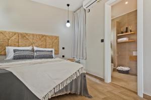 a white bedroom with a large bed with blue pillows at Kalimera Karpathos Exclusive Villas in Afiartis