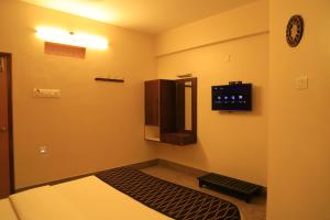 um quarto com uma televisão e um micro-ondas em TM Hotel em Madurai