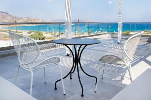 two chairs and a table on a balcony with the ocean at Kalimera Karpathos Exclusive Villas in Afiartis