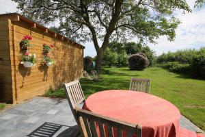 a red table with two chairs and a fence with flowers at Studio confortable à la campagne et proche de la ville in Walhain-Saint-Paul