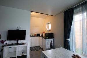 a living room with a television and a kitchen at Studio confortable à la campagne et proche de la ville in Walhain-Saint-Paul