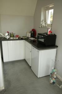 een keuken met witte kasten en een zwarte magnetron bij Studio confortable à la campagne et proche de la ville in Walhain-Saint-Paul
